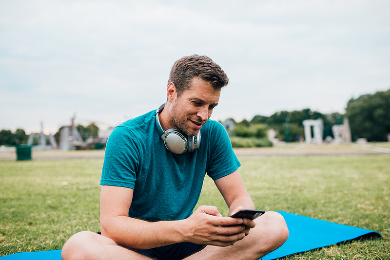 Mann beim Sport schaut auf sein Handy 